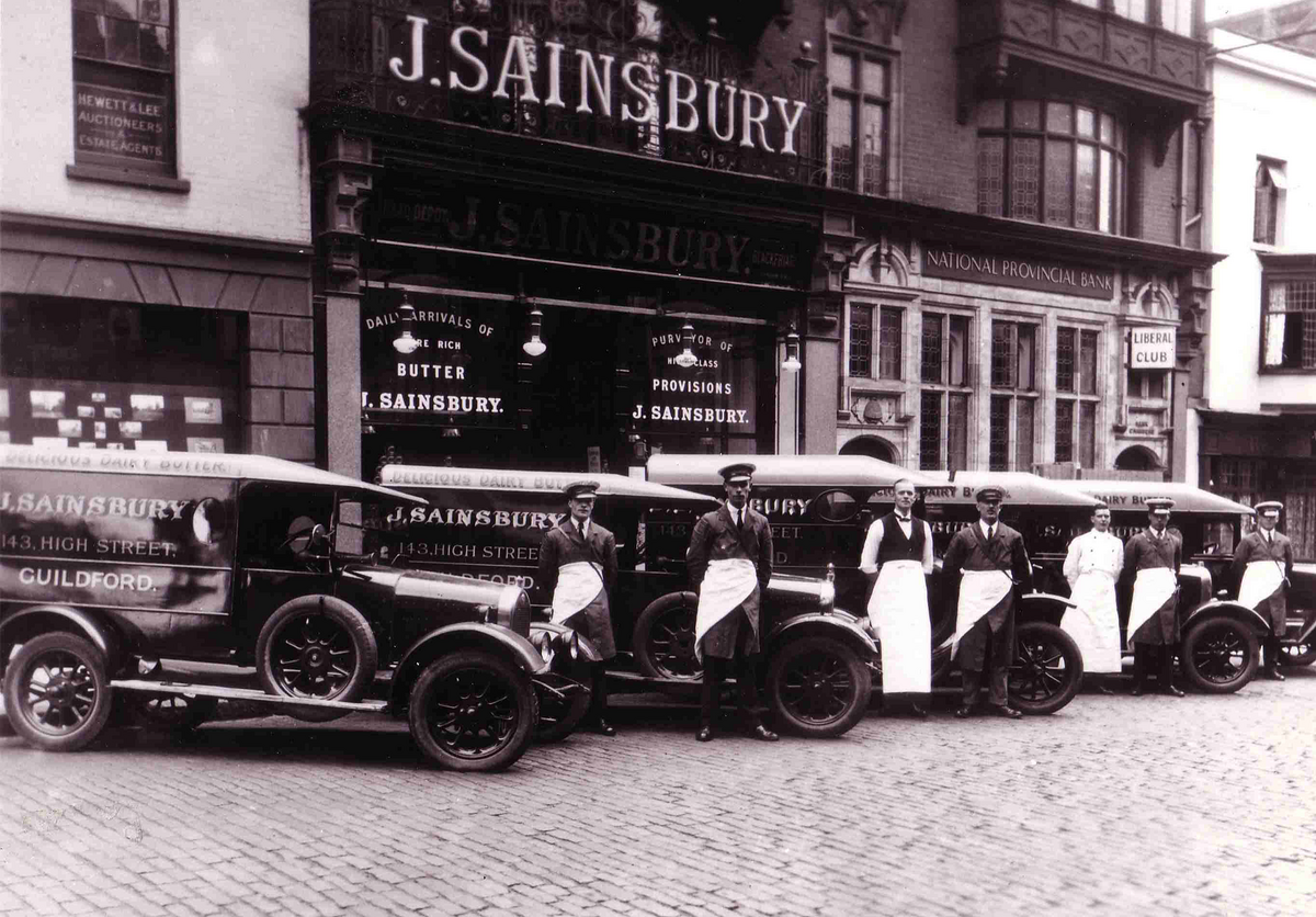 Historic Image from the Sainsbury archive, Showcasing 150 years of retail history. Men in white aprons standing out front of Sainsbury licenced shop and vehicles.